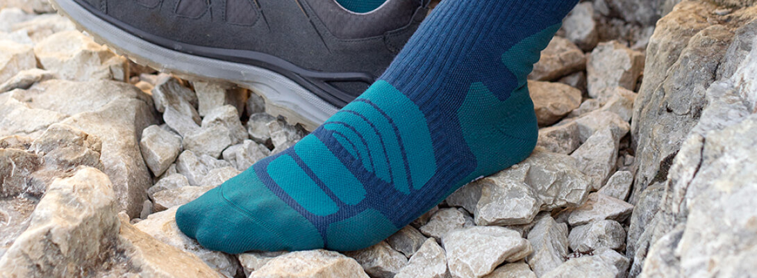 Merino-Wandersocken dunkelblau bei einer Wander-Pause Fuß in einem Merino-Wandersocken auf steinigem Untergrund