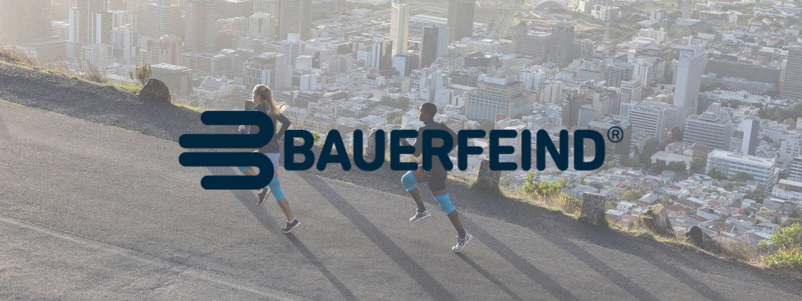 Bauerfeind: Bewegung ist unsere DNA Bauerfeind Schriftzug auf einem Bild wo zwei Läufer auf einem Berg über der Stadt laufen