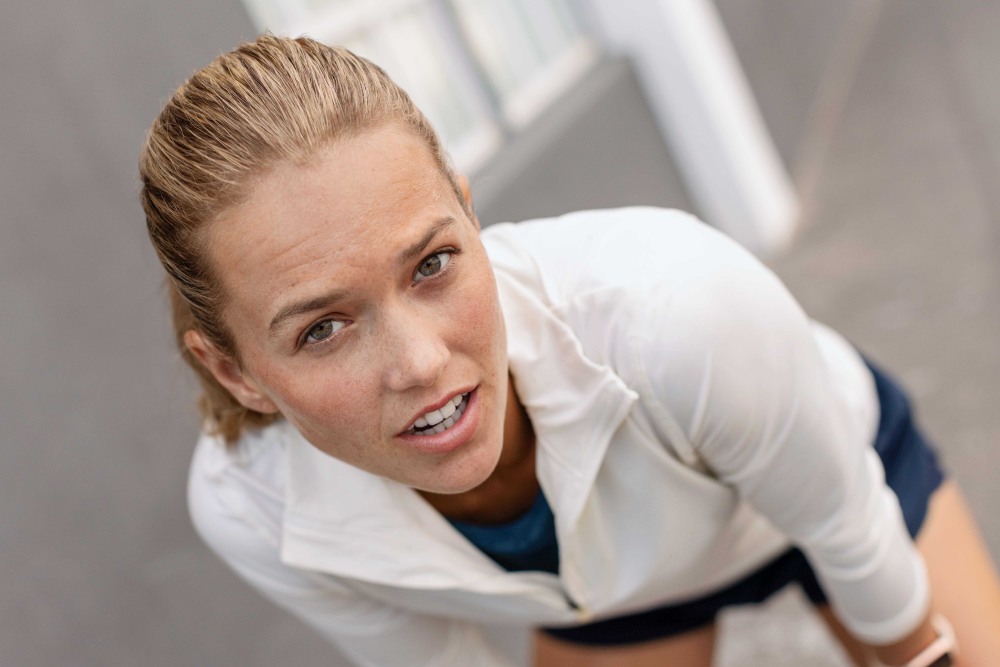 Du willst einen Marathon laufen? Dann denke über einige Punkte nach Blonde Frau mit weißem Sportpullover blickt direkt in die Kamera
