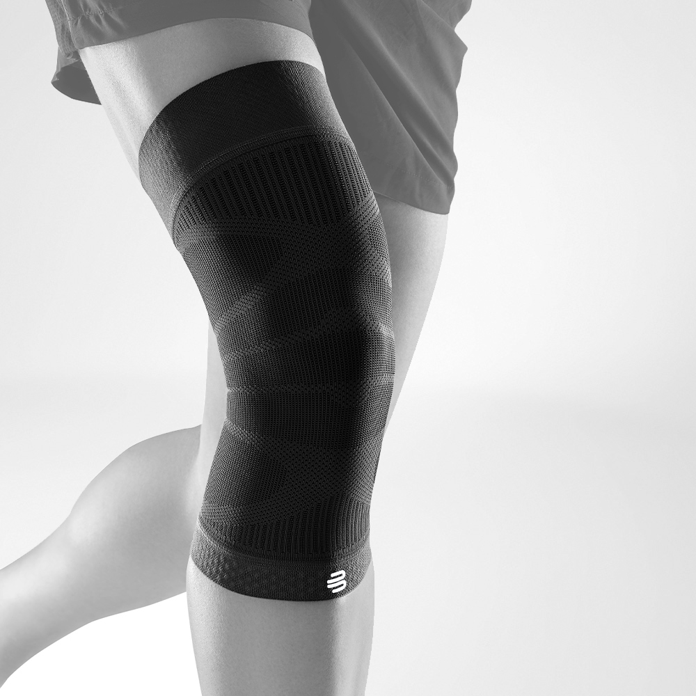 Knee Sleeve schwarz Vorderansicht schräg Komplettansicht des schwarzen Knee Sleeves an einem stilisierten grauen Bein