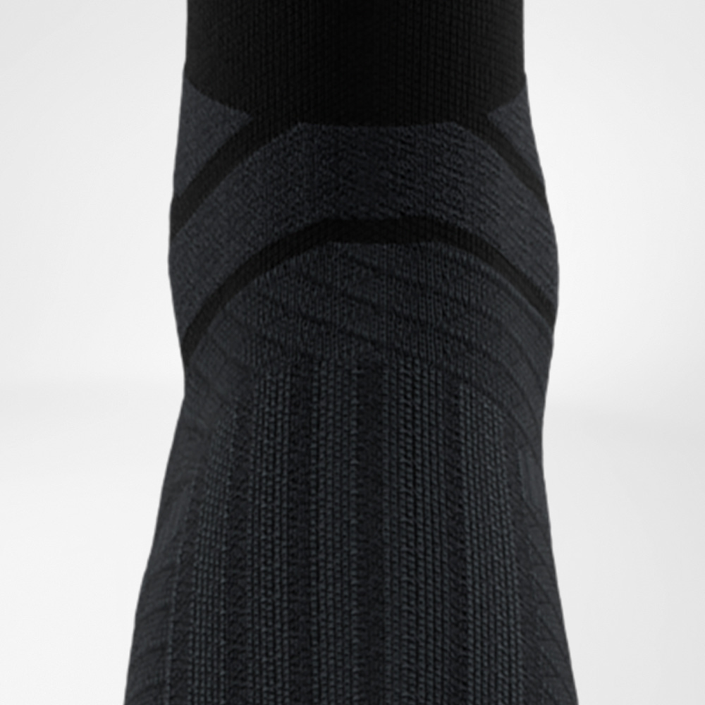 Rückansicht der schwarzen Run Performance Midcut Socke mit verstärkter Komfortzone an der Achillessehne. Die dunklen Strickmuster heben die ergonomische Polsterung hervor.