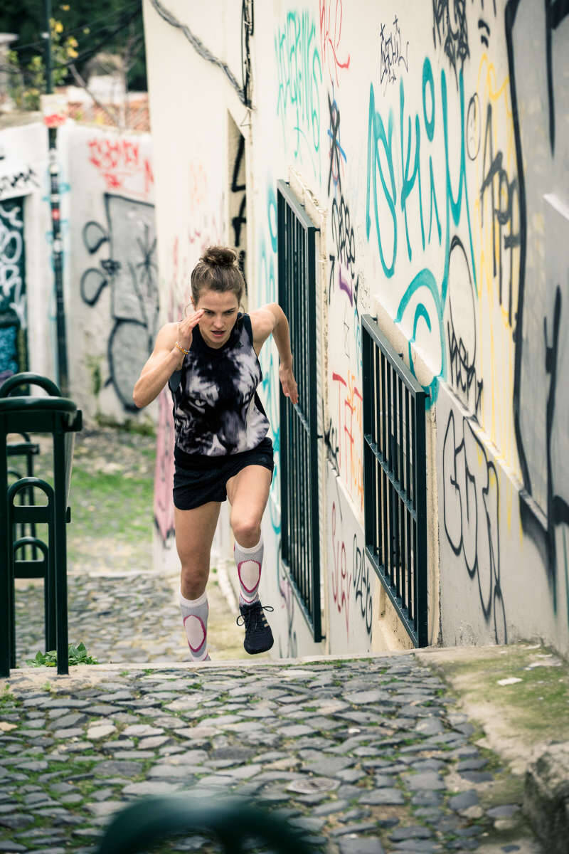 Läuferin läuft eine Treppe in einer Altstadt mit zahlreichen Graffitis an den Wänden nach oben