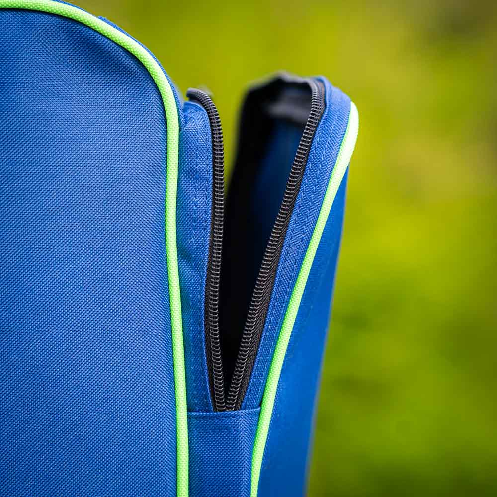 Bauerfeind Sports Skischuhtasche im Detail Nahaufnahme des Reißverschlusses der Bauerfeind Sports Skischuhtasche. Der schwarze Reißverschluss ist teilweise geöffnet und von einer grünen Kante umrahmt. Der Hintergrund ist unscharf und zeigt grüne Vegetation