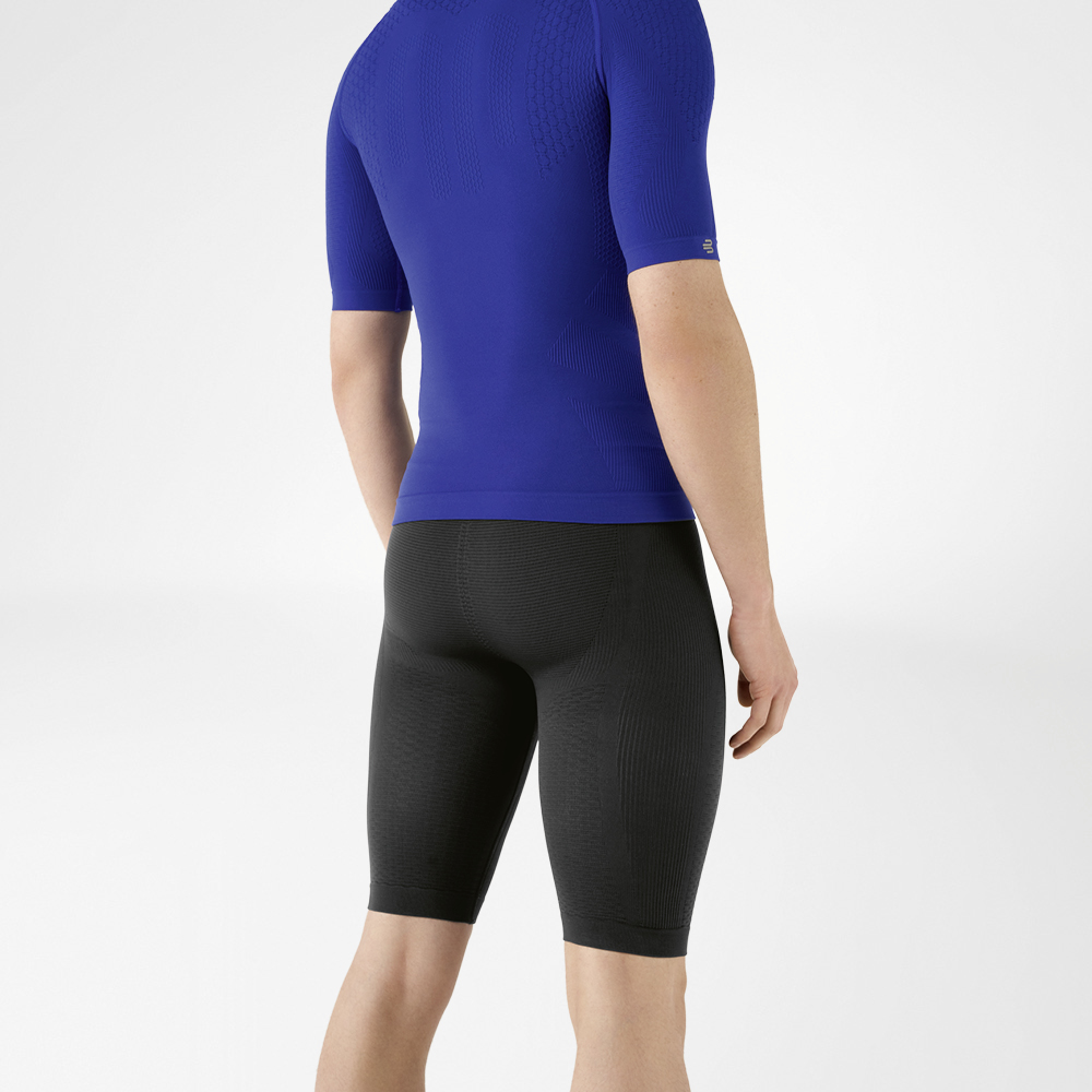 Sportoutfit mit Kompression für Männer Der Mann trägt ein eng anliegendes, blaues Shirt, das seinen Oberkörper betont, sowie eine knielange, marineblaue, eng geschnittene Sporthose, die seinen Unterkörper umschließt.