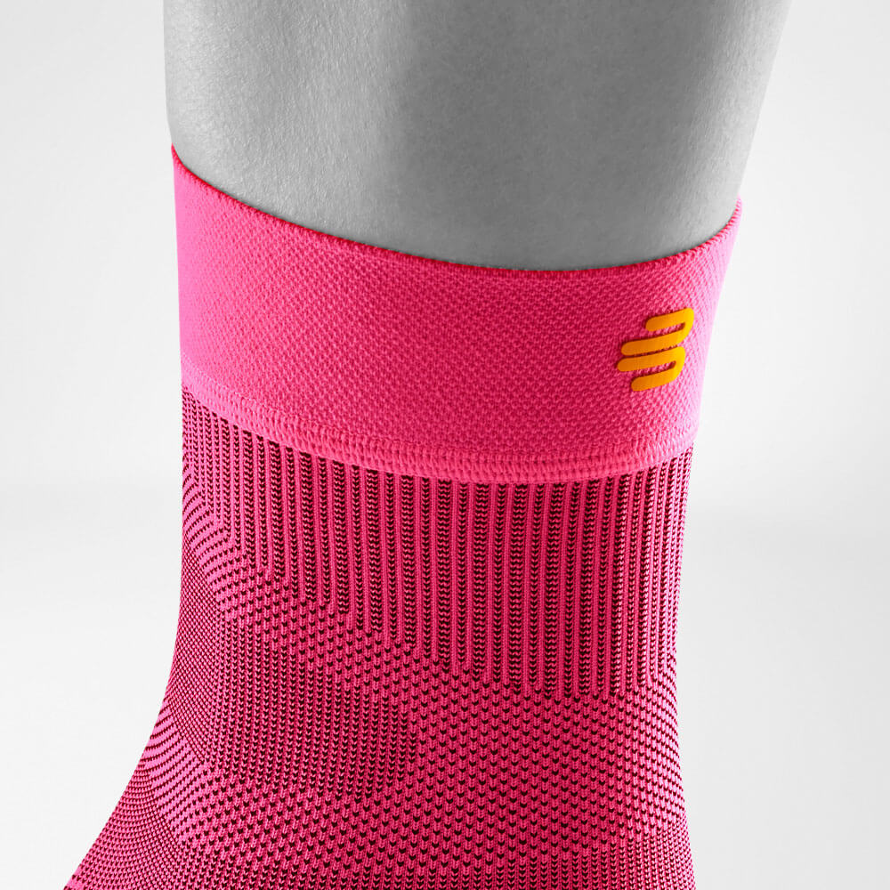 Sprunggelenksleeve pink Detail Bund Detailansicht des oberen Bereiches des pink-farbenen Sportsleeves für das Sprunggelenk inklusive Gestrickverlauf und Logo