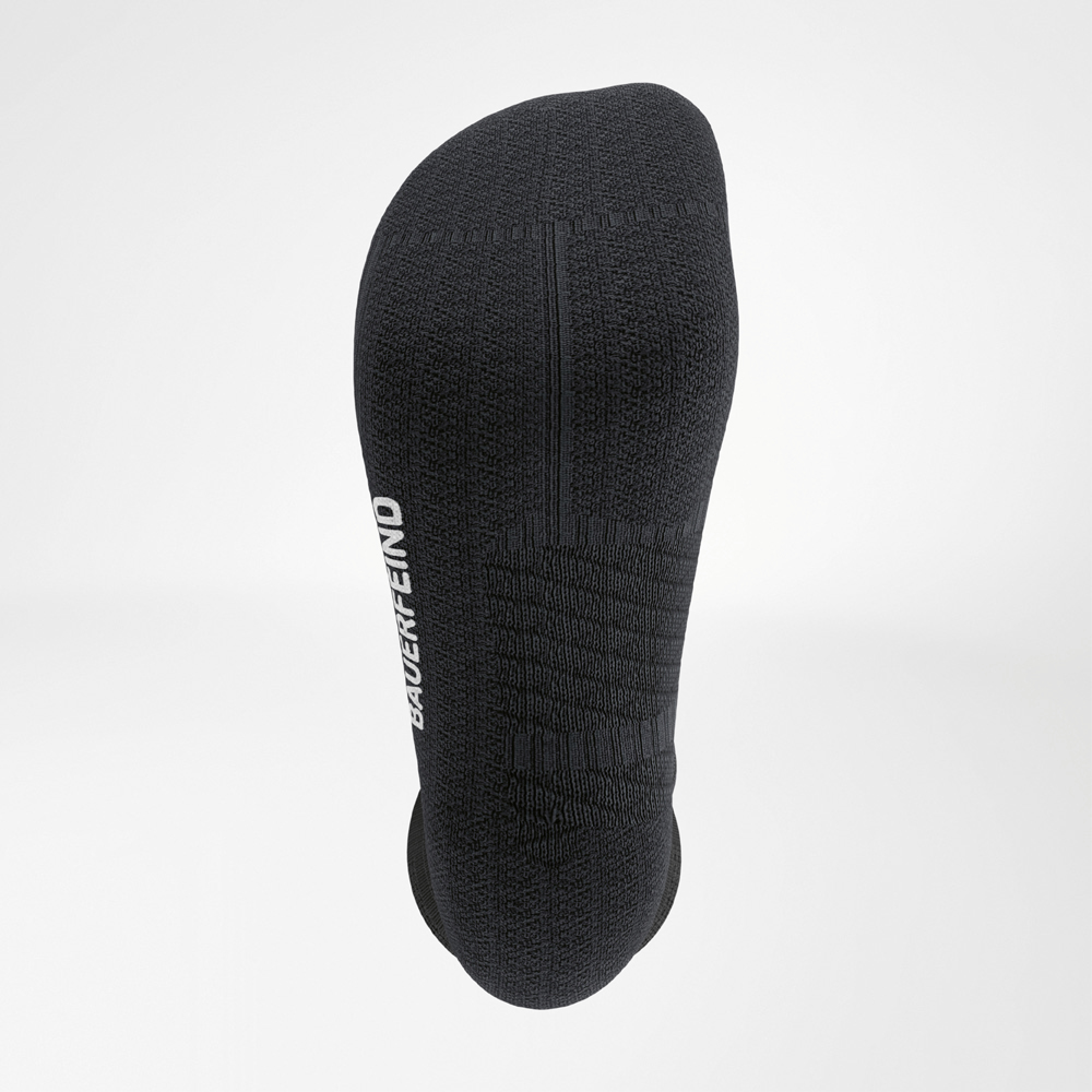 Detailaufnahme der Fußsohle einer schwarzen Laufsocke mit gepolsterter Struktur, ergonomischer Nahtführung und seitlichem BAUERFEIND-Schriftzug.