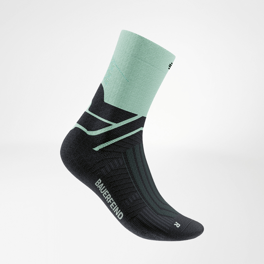 Detailaufnahme einer Laufsocke in Schwarz mit grünem Schaft und grünen Verstärkungen. Die Socke zeigt das Bauerfeind-Logo und die markante Infinity Zone für Stabilität im Sprunggelenk.