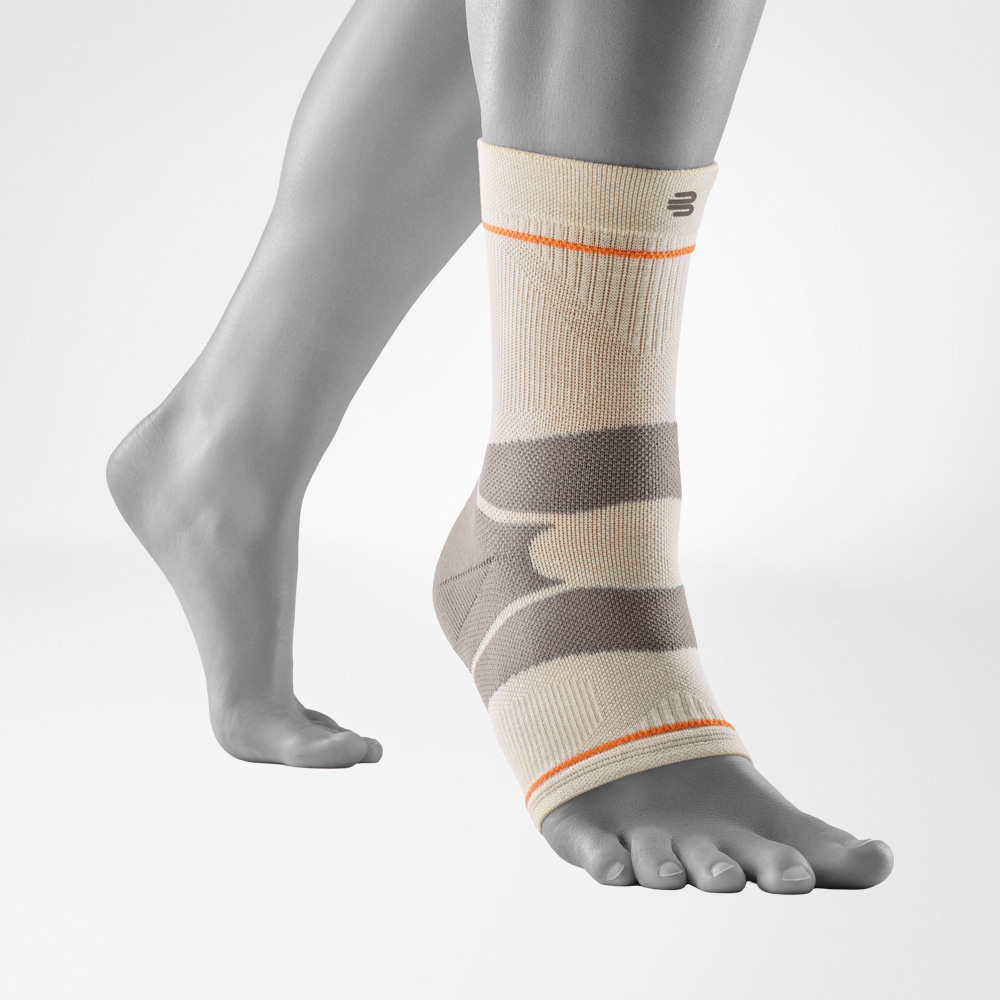 Outdoor-Compression-Ankle-Support in der Farbe Sandstone, getragen am rechten Fuß vor neutralgrauem Hintergrund. Die Knöchelbandage umschließt den Fuß und das Sprunggelenk