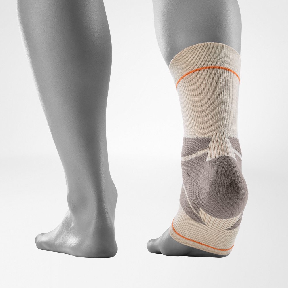 Outdoor-Compression-Ankle-Support in Sandstone-Farbe aus rückwärtiger Perspektive, getragen am rechten Fuß vor grauem Hintergrund. Die Knöchelbandage zeigt die anatomisch geformten Kompressionszonen